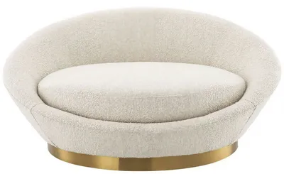 Fauteuil AURA, vue frontale montrant l'assise enveloppante et la base circulaire en laiton