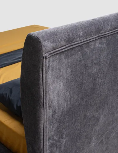 Detail of the corner of the VALEN bed's upholstered headboard